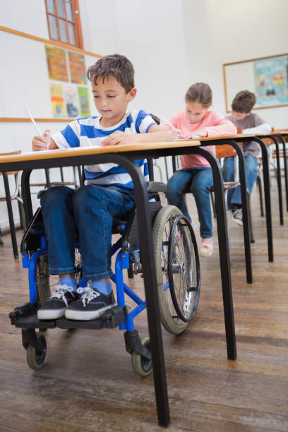 istock Disabled pupil writing at desk in classroom 819382570