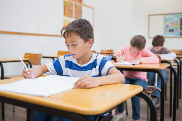 istock Disabled pupil writing at desk in classroom 819382588