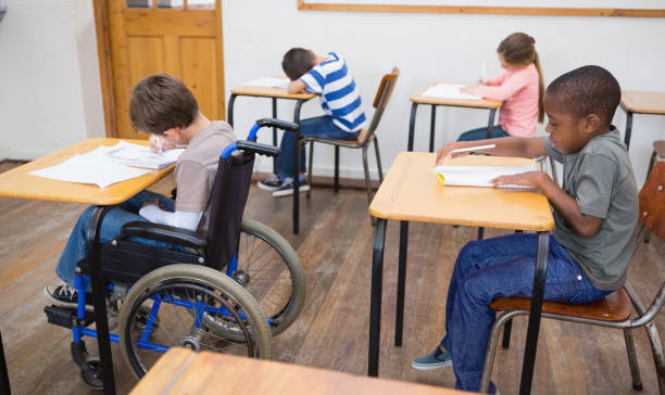 istock Disabled pupil writing at desk in classroom 819382794