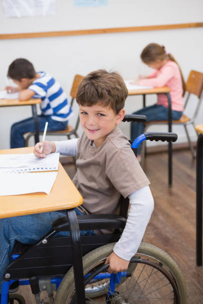 istock Disabled pupil writing at desk in classroom 819382820
