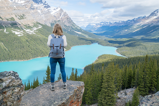 Young woman hiker on rock above mountain lake in Springtime. People success in nature concept