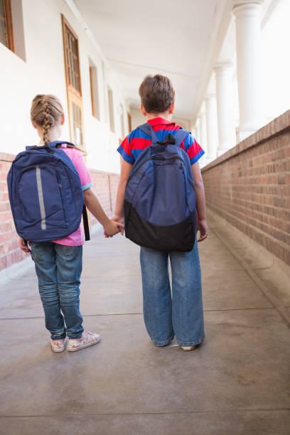 istock Cute pupils holding hands in corridor 819400226
