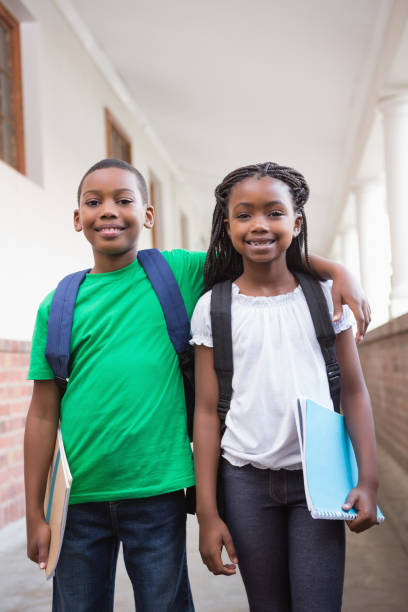 istock Cute pupils smiling at camera in corridor 819400282