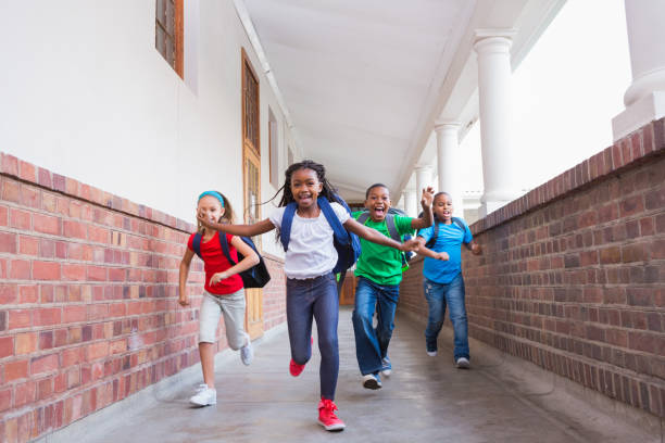 istock Cute pupils running and smiling at camera in hallway 819402552