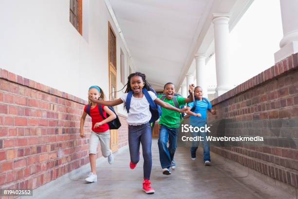 Cute Pupils Running And Smiling At Camera In Hallway Stock Photo - Download Image Now