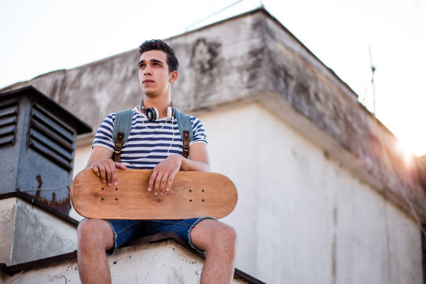 istock Young Man Sitting On Rooftop On Sunny Summer Day 819402560