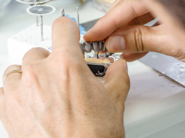 istock Dental technician making a metal structure of a dental crown or bridge. 819405916