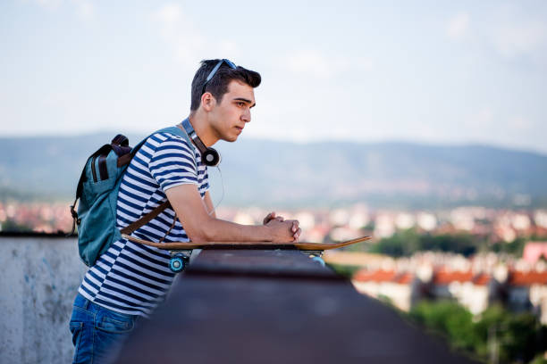 istock Hipster Guy With Skateboard Standing On Balcony 819410290