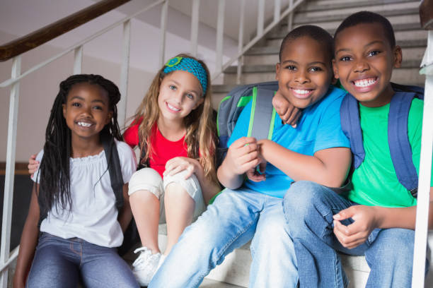 istock Cute pupils smiling at camera on the stairs 819410348