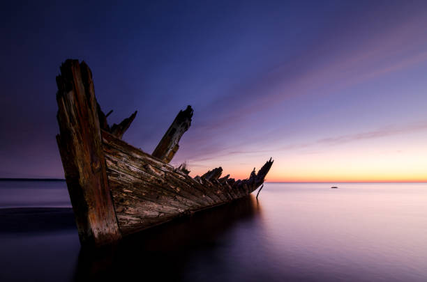 istock Sunset on the beach with an old sailboat wreck. 819410460