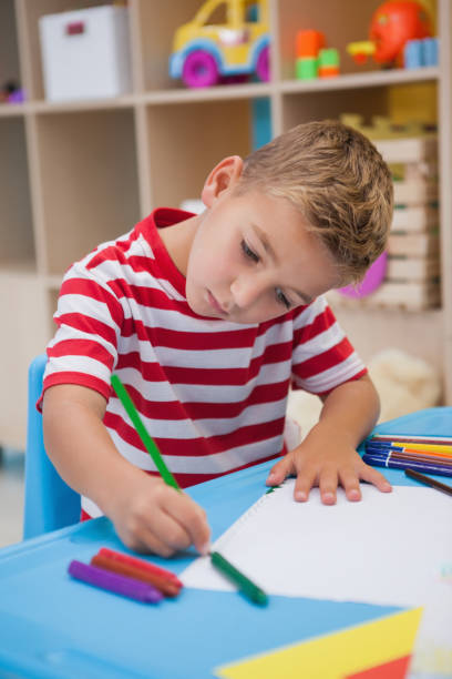 istock Cute little boy drawing at desk 819415030