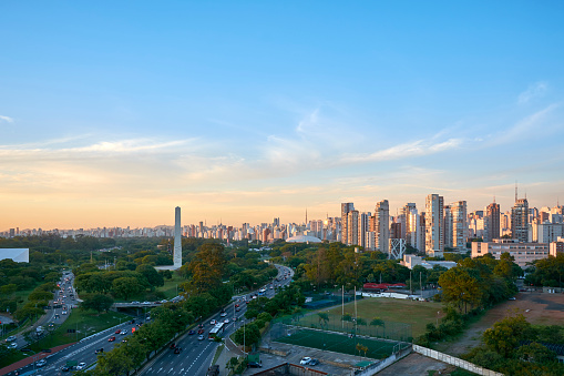Ibirapuera Park, obelisk and skyscrapers of Sao Paulo city in sunset, Brazil.