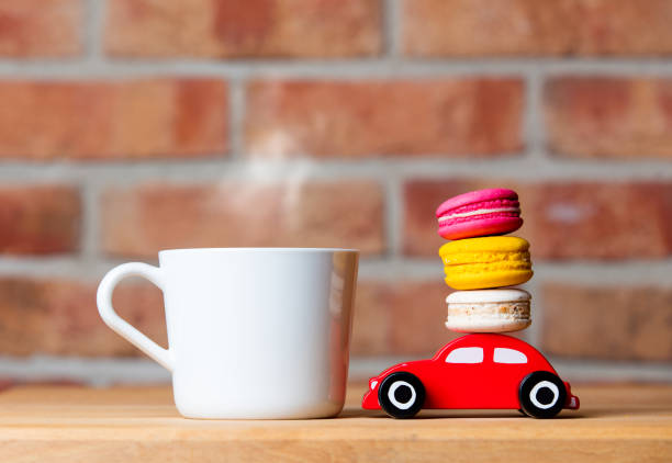 photo of colorful macaroons, cup of coffee and car shaped toy on the wonderful brick wall background