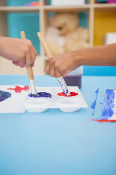 istock Cute little boys painting at table in classroom 819425316