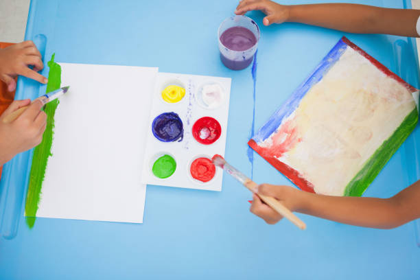 istock Cute little boys painting at table in classroom 819425358