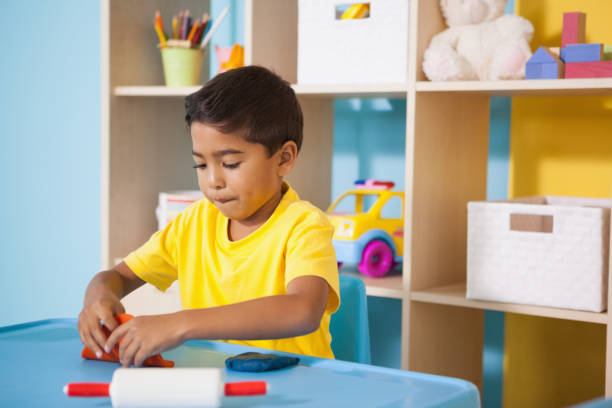istock Cute little boys playing with modelling clay in classroom 819445956