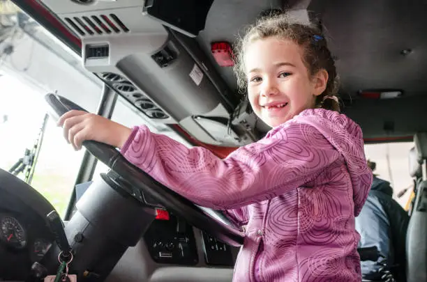 Little girl behind firetruck steering wheel