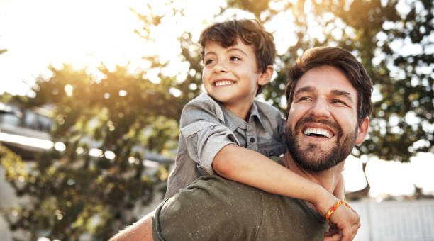 It takes a special person to be a dad Portrait of a happy father giving his little boy a piggyback ride in their backyard father stock pictures, royalty-free photos & images