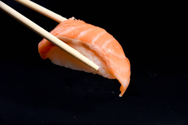 istock sushi nigiri in chopsticks over black background 819491746