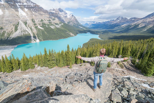 istock Young man hiker arms outstretched at mountain lake 819498380