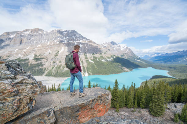 istock Young man hiker on rock above mountain lake 819500922