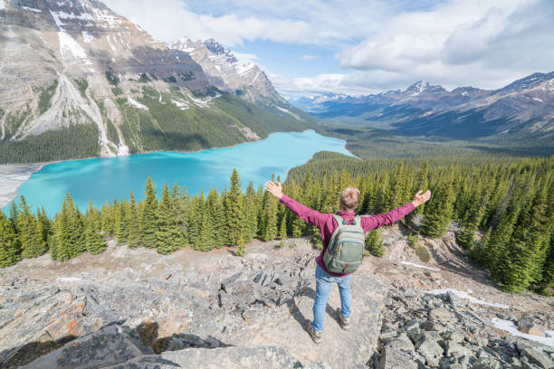istock Young man hiker arms outstretched at mountain lake 819503976