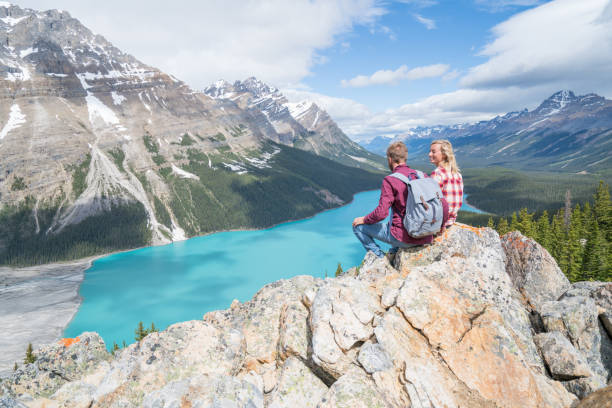 Couple of hikers overlooking mountain lake Two young people hiking in mountain lake scenery. canadian rockies stock pictures, royalty-free photos & images