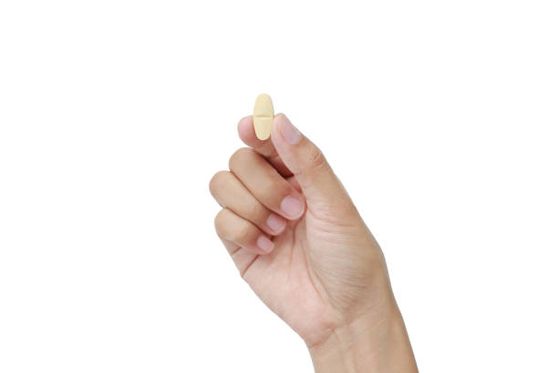 istock Hand holding yellow pill isolated on white background. 819547960