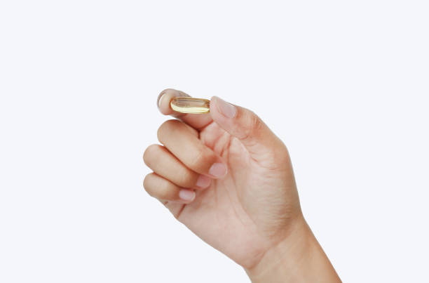 istock Hand holding yellow fish oil capsule isolated on white background. 819547998