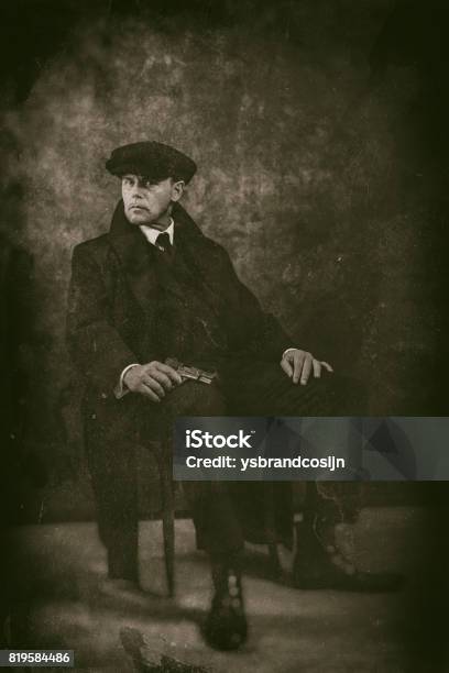 Retro 1920s English Gangster With Gun Sitting On Chair Peaky Blinders Style Stock Photo - Download Image Now