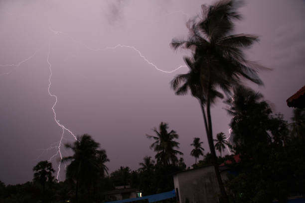 Thunder, lightning storm in the raining night background over a house and palm tree. In Mumbai