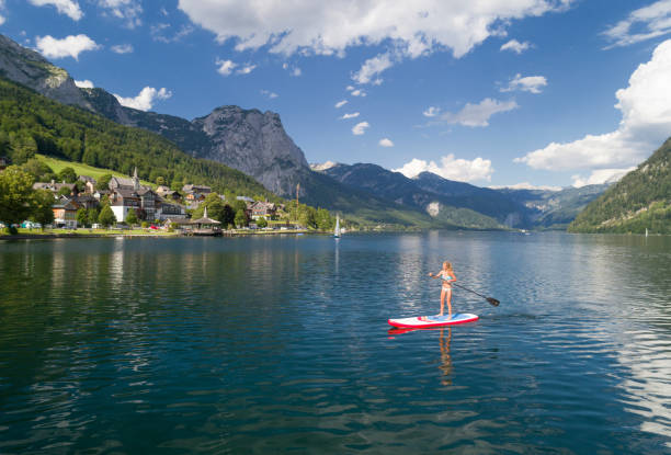 woman stand up paddling (sup) на озере грундзее, австрия - bad aussee стоковые фото и изображения