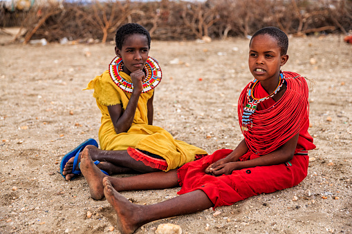 Two African little girls from Samburu tribe, resting on savanna. Samburu tribe is one of the biggest tribes of north-central Kenya, and they are related to the Maasai.