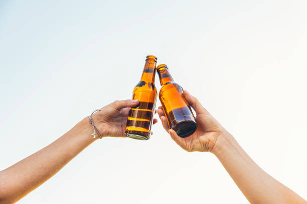 saludos amigas tintinear botellas de cerveza. - clunking fotografías e imágenes de stock
