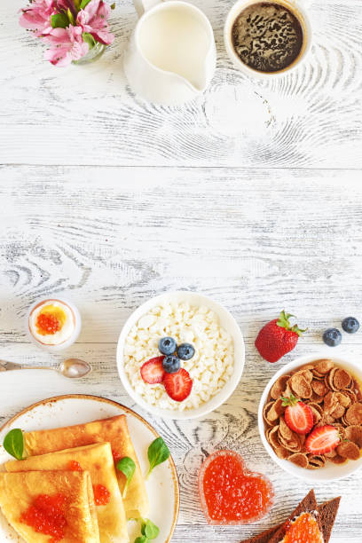 istock Crepes with caviar, boiled egg, cottage cheese, cereal with fresh berries and coffee on white table with copy space. 819611916