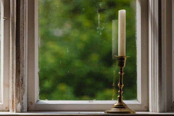 istock Old vintage window and vertical candle in candlestick 819612254