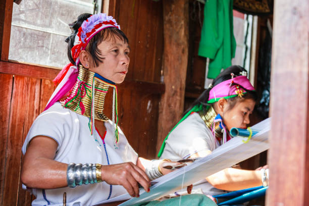 Unidentified Padaung senior woman wearing the traditional metal rings around her neck, INLE LAKE,MYANMAR-FEBRUARY 15,2016 : Unidentified Padaung senior woman wearing the traditional metal rings around her neck, working at a weaving in village of Inle lake, Shan state, Myanmar. unidentified padaung karen tribe woman weave on traditional device stock pictures, royalty-free photos & images