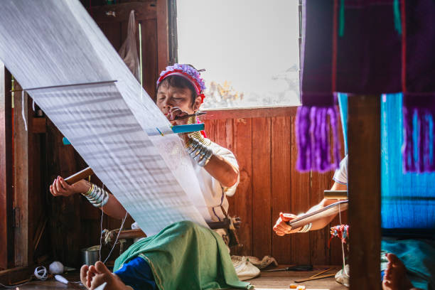 Unidentified Padaung senior woman wearing the traditional metal rings around her neck, INLE LAKE,MYANMAR-FEBRUARY 15,2016 : Unidentified Padaung senior woman wearing the traditional metal rings around her neck, working at a weaving in village of Inle lake, Shan state, Myanmar. kayan neck rings stock pictures, royalty-free photos & images