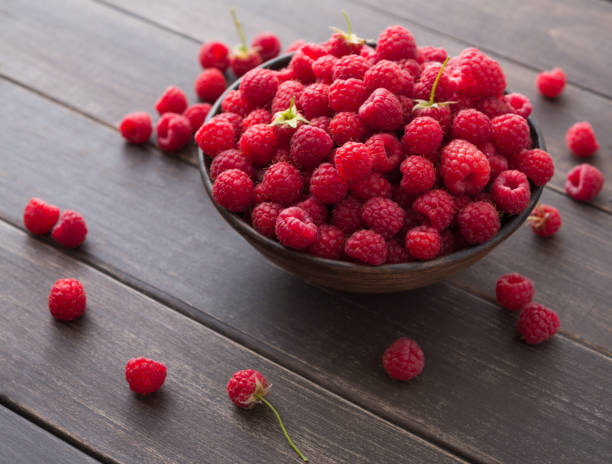 istock Red fresh raspberries on brown rustic wood background 819624820