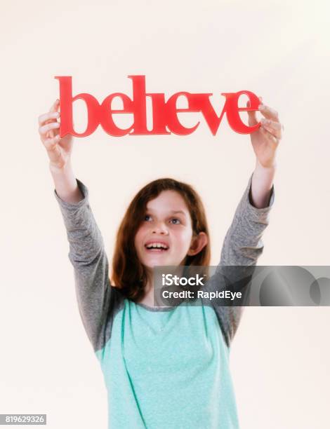 Believe Says Threedimensional Sign Held Aloft By Smiling Preteen Girl Stock Photo - Download Image Now