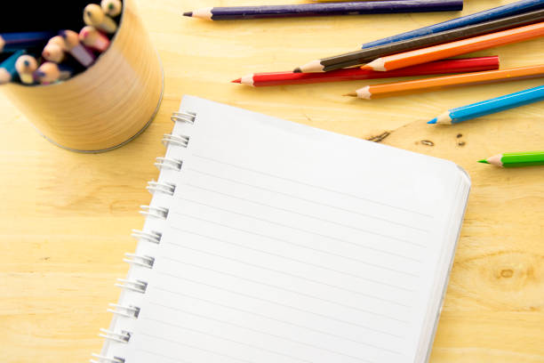istock Top view notebook paper. Colorful colored Pencils on wooden table. 819632746