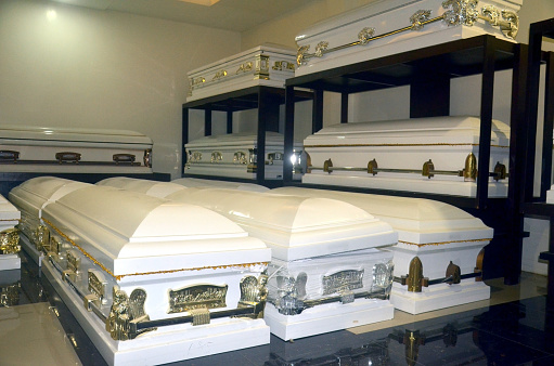 Photograph image of several white coffins or caskets in storage room.