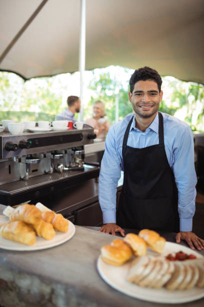 istock Smiling waiter standing near counter at restaurant 819636766
