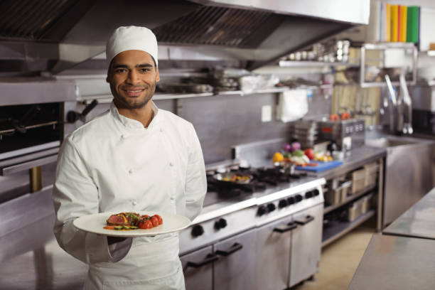 istock Smiling chef holding delicious dish in kitchen 819640186