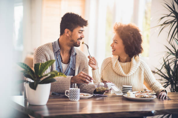 istock Young black couple in love sharing a meal at dining table. 819643684