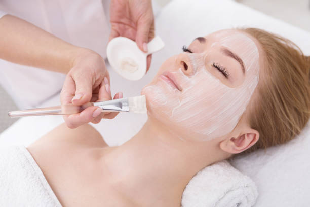 istock Woman gets face mask by beautician at spa 819644128