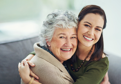 Portrait of a happy young woman spending time with her elderly relative at home