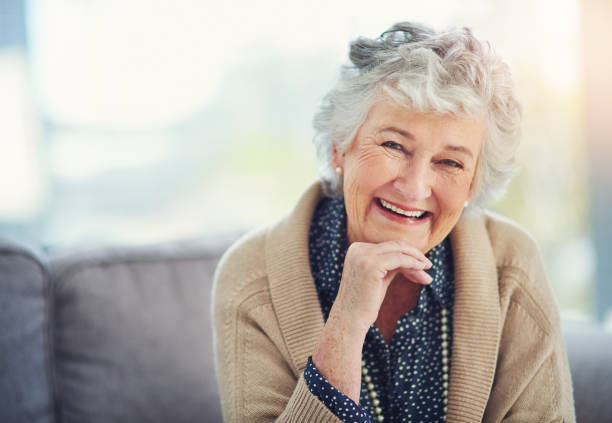 Life hasn't changed my smile one bit Portrait of a happy senior woman relaxing on the sofa at home only senior women stock pictures, royalty-free photos & images