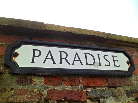 Close-up of old-fashioned style road name sign saying 'Paradise'. Black border and text with white background. Is it heavenly to live there? Very possibly. England, UK.