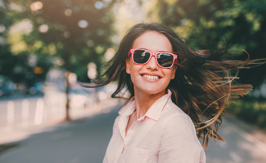 Portrait of a happy young woman with pink glasses outdoors.